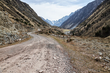 Rocky gravel road in the hillside leading into the mountains, bottom view. Early spring in nature