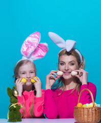 Easter holidays. A mother and her daughter painting Easter eggs. Happy family preparing for Easter, wearing easters bunny ears.