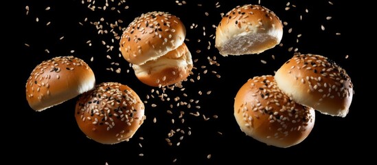 Flying burger buns with sesame seeds on black background. - obrazy, fototapety, plakaty