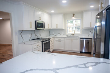 A light and bright newly remodeled white kitchen with quartz countertops, white shaker cabinets and...