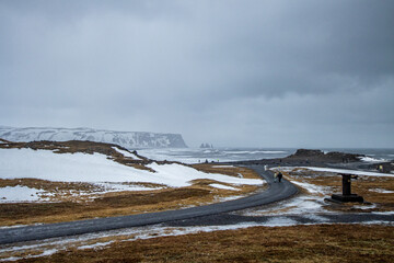 Driving in Iceland in Winter time, tourist trip around 1 Ring Road. Empty road stretching into the horizon with a snowy landscape. Iced pavel road, snow and glacier in self driving tour in Iceland.
