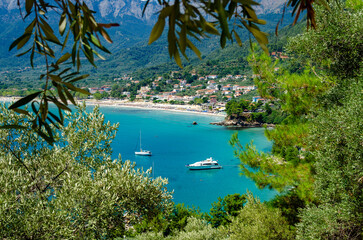 Boats sailing amidst lush vegetation and majestic mountains in Thassos