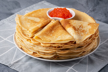 Pancakes with red caviar on grey background