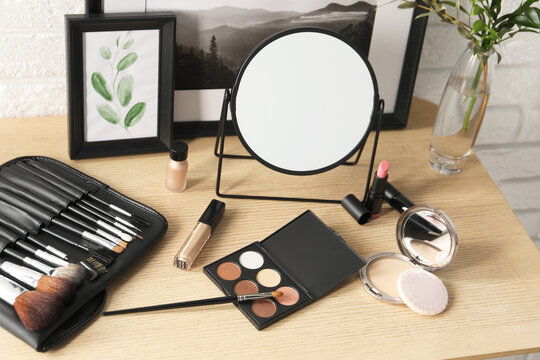 Mirror, makeup products and pictures on wooden dressing table