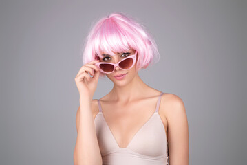 Naklejka premium Girl with pink wig. Close-up portrait of lovely pretty girl isolated over studio background. Beauty woman with perfect skin. Makeup and cosmetics. Natural makeup for beauty salon.