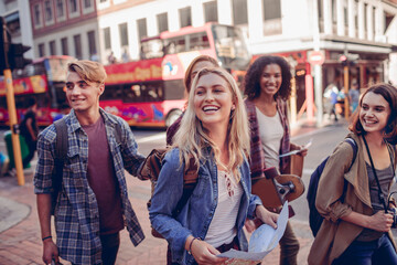 Diverse group of friends walking in the city with a map