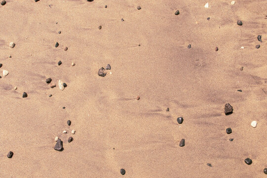 Arena mojada tras el reflujo de la ola en la playa. Arena y peque&ntilde;os cantos rodados arrastrado por la marea en la cala de Enmedio en N&iacute;jar, Almer&iacute;a, Espa&ntilde;a.