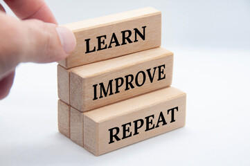 Learn, improve and repeat text on wooden blocks with white cover background. Improvement concept.