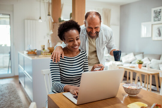 Diverse middle aged couple using laptop for online shopping at home