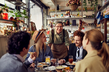 Diverse young people sharing meal in cozy restaurant