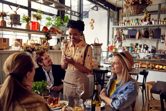 Smiling waitress writing order from customers at restaurant