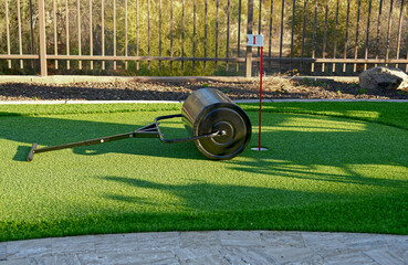A sod roller on an artificial turf backyard putting green.