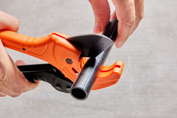 Using pipe cutter with ratcheting mechanism when installing sprinkler water line, close-up of...