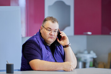 Bad news on phone, an overweight man in his 40s listens to his interlocutor via smartphone.