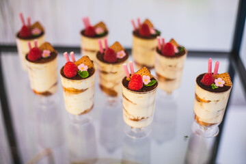 Desserts with whipped cream , fresh fruits in transparent cups on sweet table at wedding, party,. 