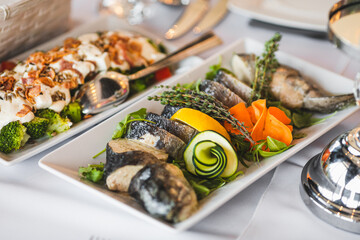 Menu for holidays, weddings. Rectangular plates with cold fish snacks vegetables in restaurant.