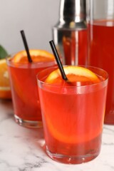 Aperol spritz cocktail, orange slices and straws in glasses on white marble table, closeup
