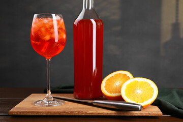 Aperol spritz cocktail and ice cubes in glass and bottle on wooden table