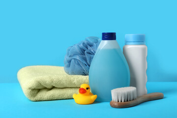 Baby cosmetic products, bath duck, accessories and towel on light blue background