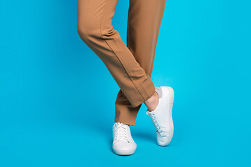 Close up cropped photo of white leather stylish sneakers combination with brown pants formal style...