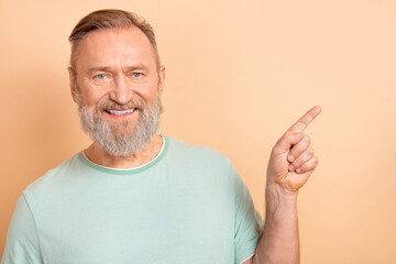 Photo of cheerful satisfied man dressed trendy clothes showing empty space offer proposition isolated on beige color background