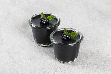 Vegan dessert. Black Matcha Cream jelly pudding, Panna Cotta decorated with black berries, in...