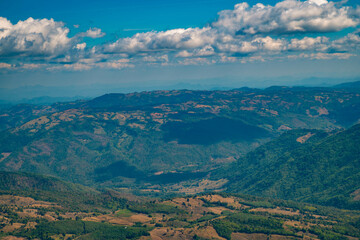 Fototapeta premium The stunning view in Forest Park from a tourist's standpoint as they go down a hill with background of blue sky, Rainforest, Thailand. Bird's eye view. Aerial view. 