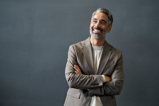 Happy Middle Aged Business Man Looking Away At Copy Space. Smiling Confident 50 Years Old Mature Professional Businessman Executive Ceo Manager Or Entrepreneur Standing At Gray Office Wall Background.