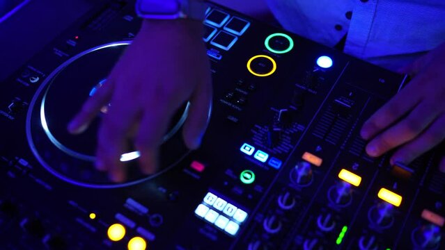 La mano del hombre en la mesa de mezclas de m&uacute;sica de DJ. Scratching. Imagen en c&aacute;mara lenta