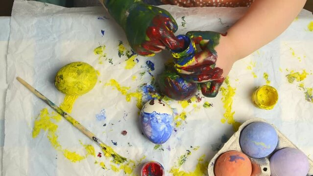 A little girl paints eggs for Easter. Preparation for the Easter holidays.