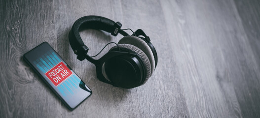 Headphones and smartphone playing audio, wooden background. Web radio play music. Streaming podcast