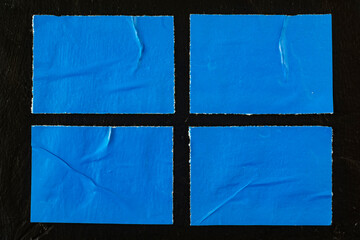 Four blue posters on a black wall.