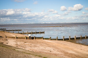 Sunny day on the beach with person walking alone