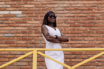 A black woman dressed in a white dress walks along a city street. - 738241338