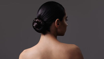 Portrait of a brunette girl with a bun hairstyle. Back view. - 738242102