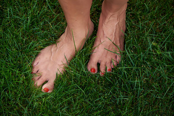 Bare female feet walking on green grass