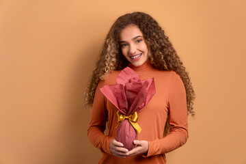 cheerful young woman showing easter egg in beige colors. holiday, easter, celebration concept.
