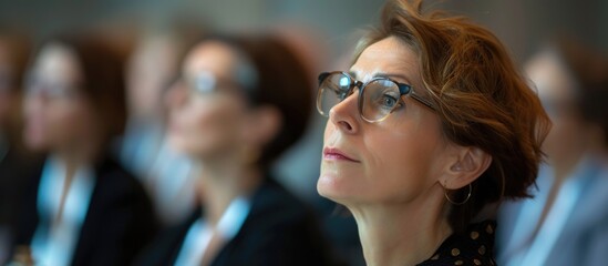 Caucasian woman listening attentively at HR forum, focused on presenter.