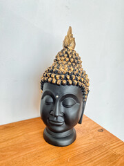 Buddha head statuette standing on table, black head of Indian deity, yoga creed, jade statue.