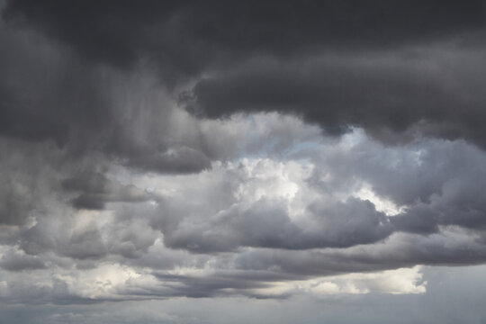 Grey storm clouds on a blue sky, rays of light on grey clouds