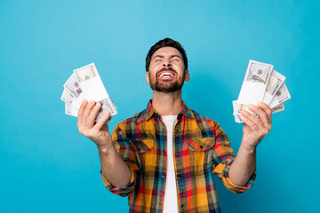 Portrait of funny guy with stubble showing dollars win gambling shout eyes closed have lot of fun isolated on blue color background - obrazy, fototapety, plakaty