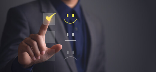 Business man is touching the virtual screen on the happy yellow face smile icon to give...