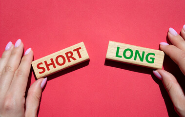 Short vs Long symbol. Concept word Short vs Long on wooden blocks. Businessman hand. Beautiful red background. Business and Short vs Long concept. Copy space