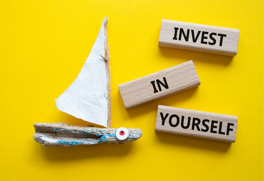 Invest in Yourself symbol. Concept words Invest in Yourself on wooden blocks. Beautiful yellow background with boat. Business and Invest in Yourself concept. Copy space.