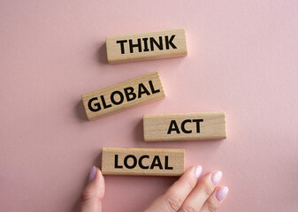 Think global act local symbol. Wooden blocks with words Think global act local. Beautiful pink background. Businessman hand. Business and Think global act local concept. Copy space.