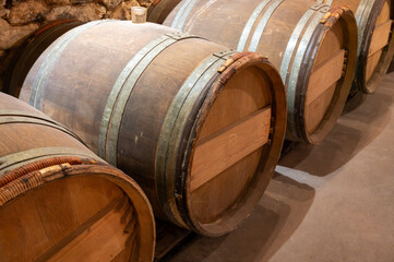 Wine cellar with wooden barrels in old wine domain on Sauternes vineyards in Barsac village...