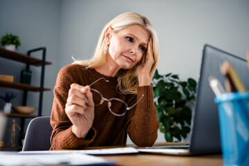 Portrait of worried pensioner business woman touch head take off her eyeglasses when looking...