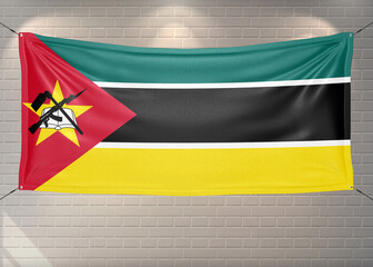 Mozambique national flag cloth fabric waving on beautiful bricks Background.