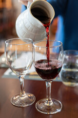 Pouring yound red beaujolais wine in glass during celebration of end of harvest and first sale...