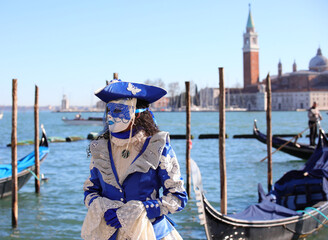 Venice, VE, Italy - February 13, 2024: masquerade woman with luxurious dress of white and blue...